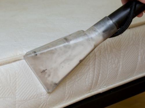 Mattress being cleaned with an upholstery tool