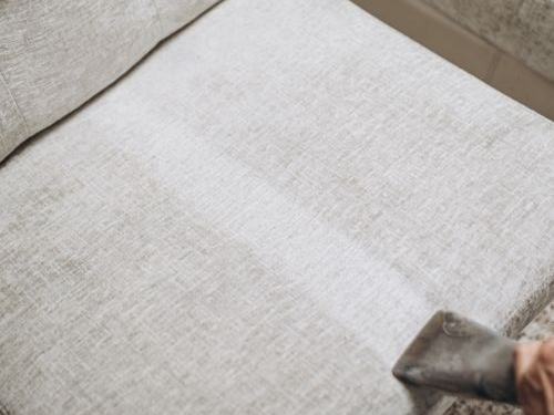 Light fabric couch seat being cleaned
