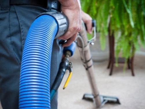 Cleaner using a carpet extraction wand on a beige carpet