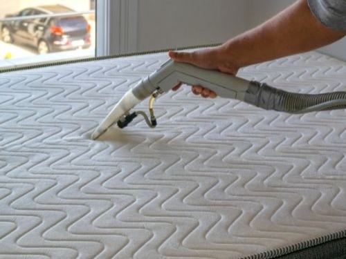 Quilted mattress being deep cleaned with an extraction tool